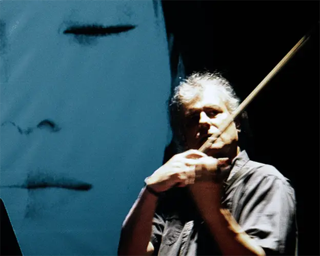 Mark Zaki performing violin in front of a blue video projection