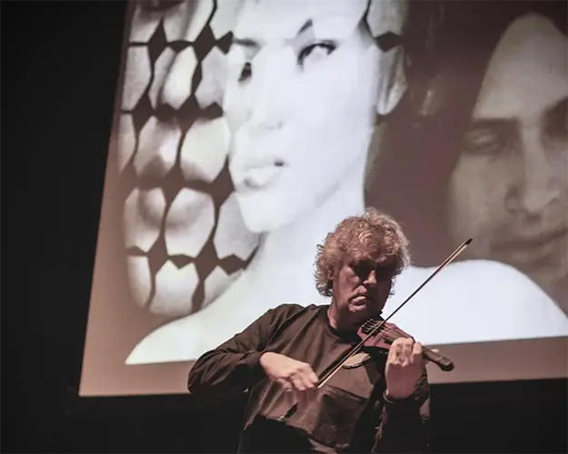 Mark Zaki performing violin with projected video