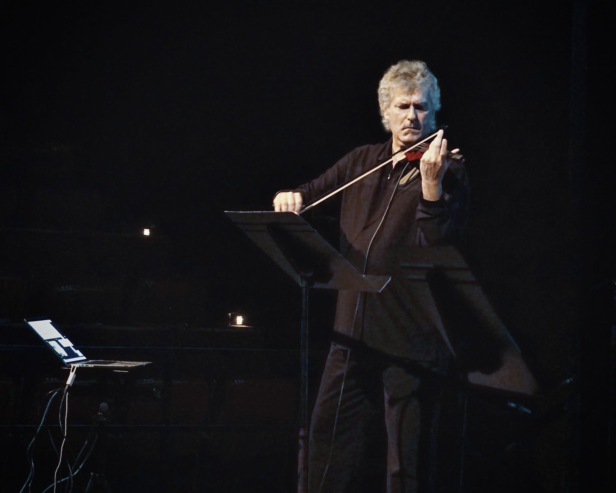 Mark Zaki performing violin with live electronics on a darkened stage